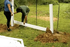 Person installing a PVC fence with tools and materials